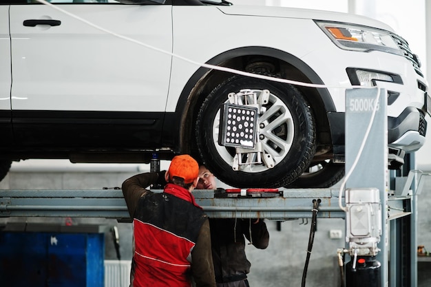 American SUV car on stand for wheels alignment camber check in workshop of service station