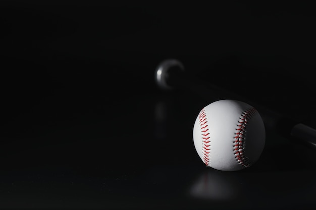 American traditional sports game. Baseball. Concept. Baseball ball and bats on a black table.