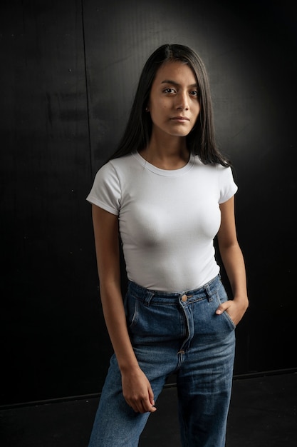 American vertical shot of a serious black haired Latina woman wearing a bluejean and a white Tshirt