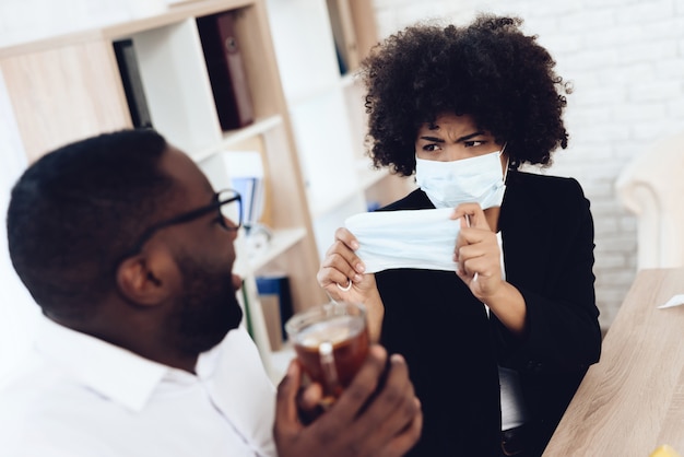 American woman gives medical mask to sick coworker.