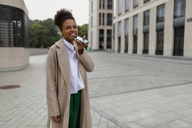 American young curly businesswoman with laptop and headphones outdoors