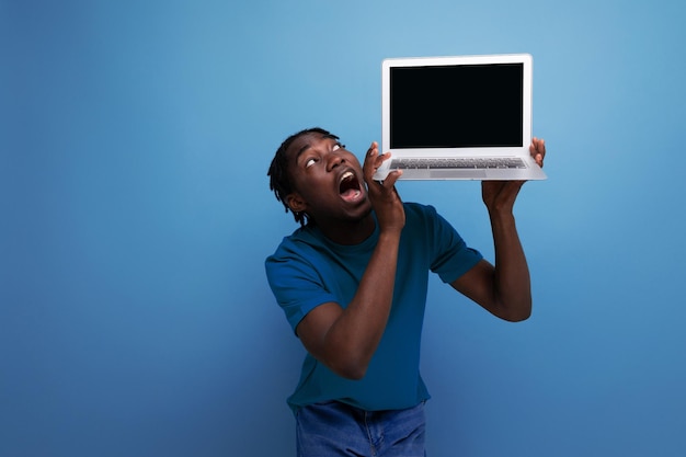 American young male brunette consultant in casual tshirt shows a laptop for advertising