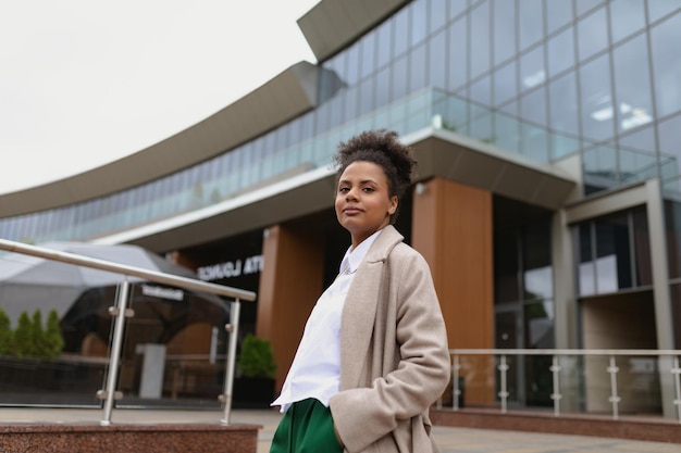 American young woman designer stands thoughtfully in front of a glass business center