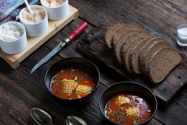 Americanstyle corn and tomato soup on a rustic table with rye bread