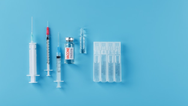 Ampoule of vaccine medicine with a syringe on a blue