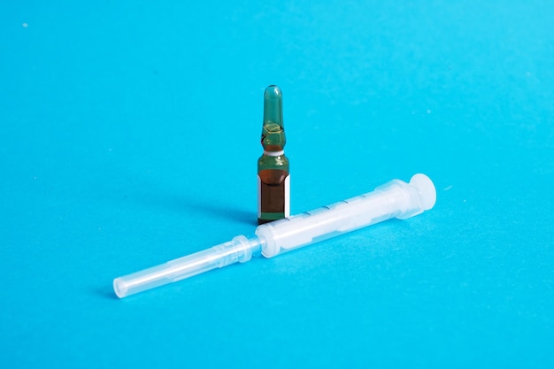 Ampoule with medicine and syringe on blue background