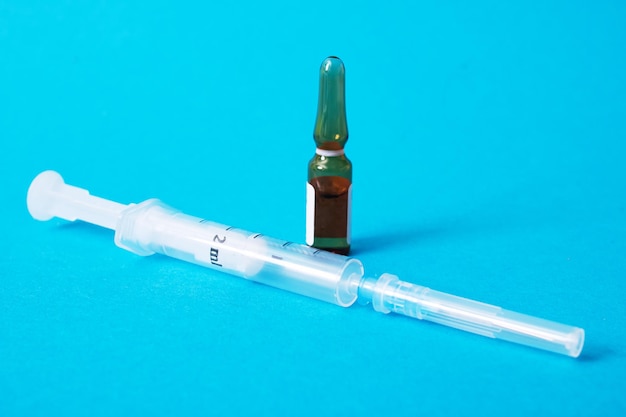 Ampoule with medicine and syringe on a blue background