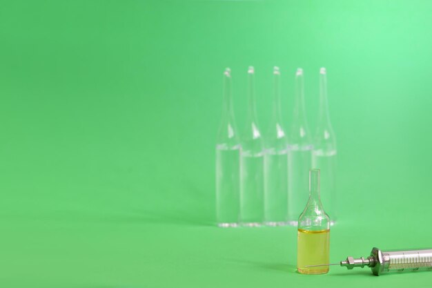 ampoules bottle in solution and syringe Medical instruments on a green Preparing for vaccination