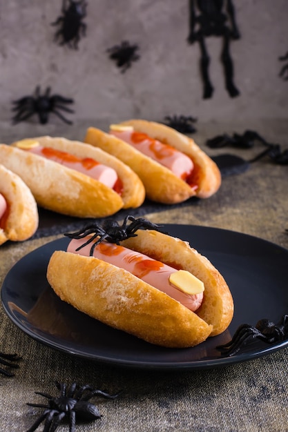 An amputated sausage finger in ketchup in a bun on a plate Halloween recipe Vertical view