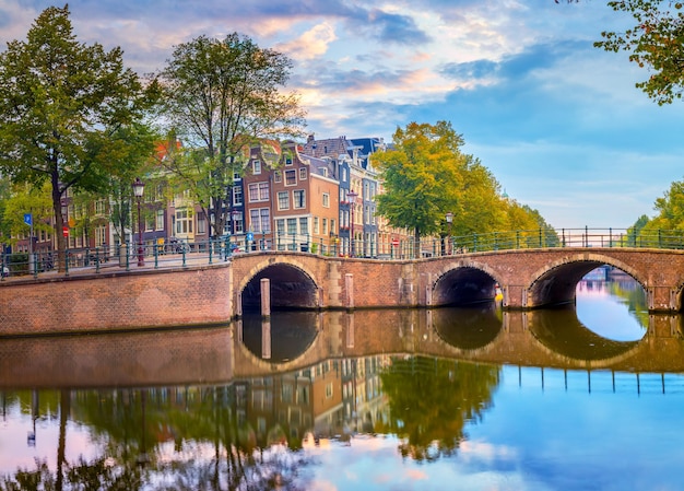 Amsterdam Downtown Beautiful sky at sunrise old houses canals and bridges Calm reflections in the water Heart of Amsterdam