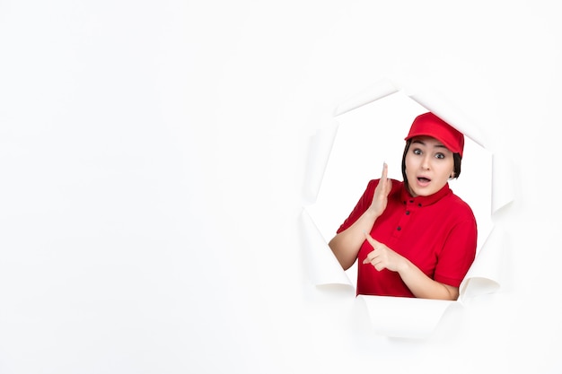 Amused female courier in red uniform on white