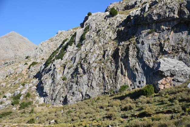 ancient cave homes in gray rock on blue sky background