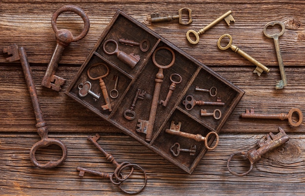 Ancient keys in a wooden box on a vintage wooden background.