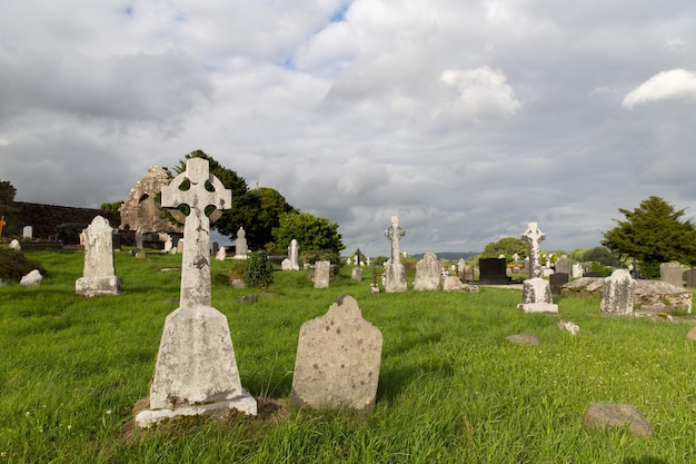 ancient monument and burial concept - old headstones and ruins on celtic cemetery graveyard in ireland