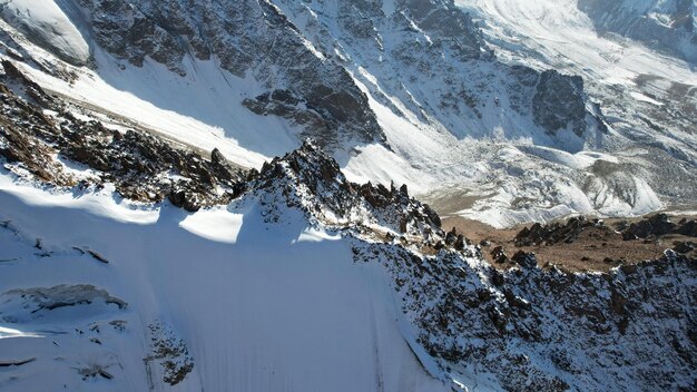 An ancient snow glacier among high mountains. In places there are steep cliffs and large rocks.