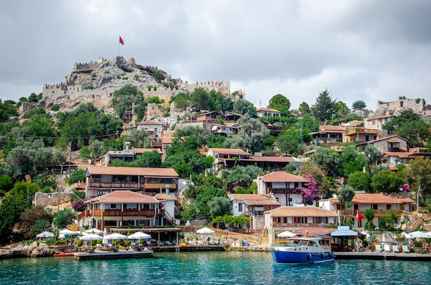 Ancient village of Simena with castle on mountain. Boat dock, beautiful landscape.