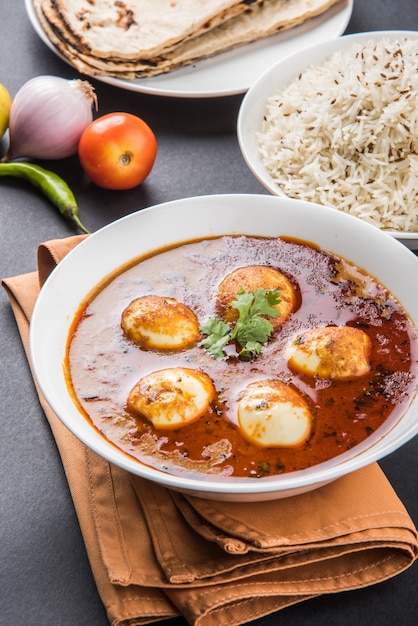 Anda Curry or Egg masala gravy, indian spicy food or recipe, served with Jeera Rice,roti or naan, selective focus. Over colourful or wooden table top