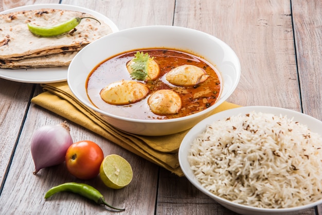 Anda Curry or Egg masala gravy, indian spicy food or recipe, served with Jeera Rice,roti or naan, selective focus. Over colourful or wooden table top