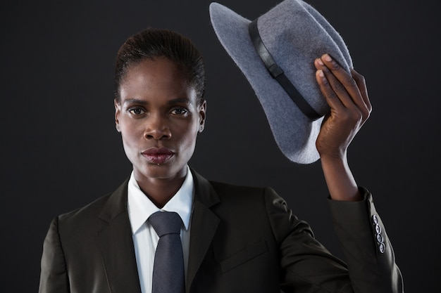 Androgynous man holding a hat against grey wall