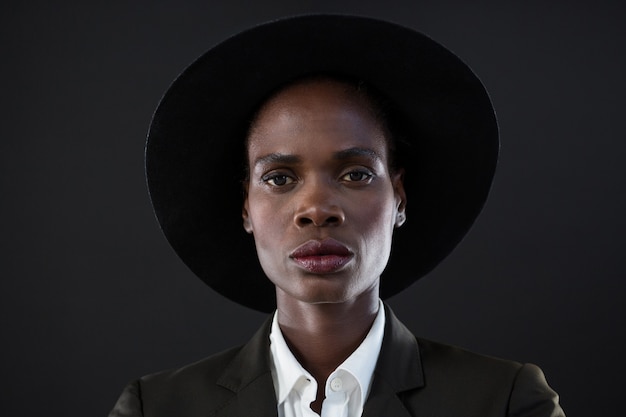 Androgynous man in suit posing against grey wall