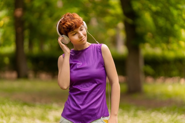 Androgynous woman listening to music and adjusting headphones