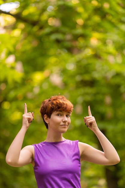 Androgynous woman pointing up in a park