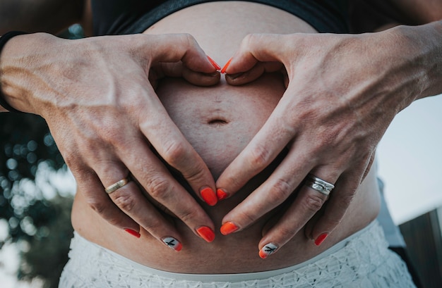 Ands of pregnant woman and her husband in heart shape