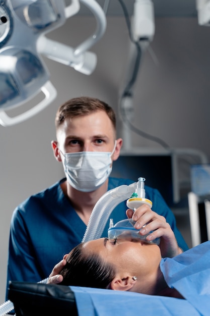 Anesthesiologist making ingalation anesthesia for patient. Doctor puts a mask on the patient before starting operation