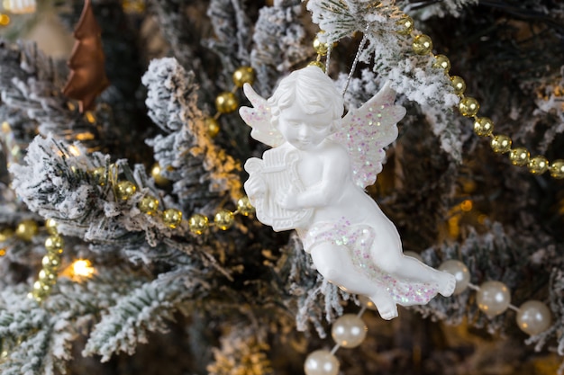 Angel figurine and golden beads hang on a Christmas tree