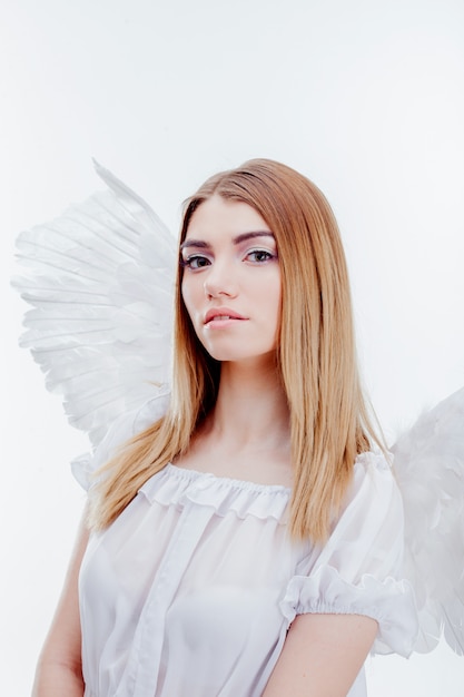 An angel from heaven. Young, wonderful blonde girl in the image of an angel with white wings. Portrait close-up