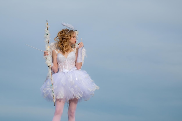 Angel teen with arrow and wings Charming curly little girl in white dress and wings angel cupid girl