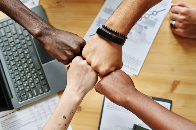 Above angle of four hands of young intercultural employees