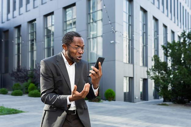 Angry african american boss arguing and shouting while talking on the phone senior man in business