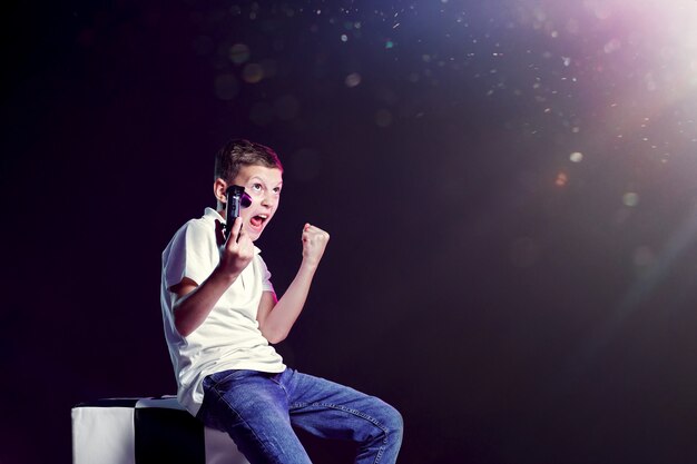 Angry boy sitting with gamepad and showing fist