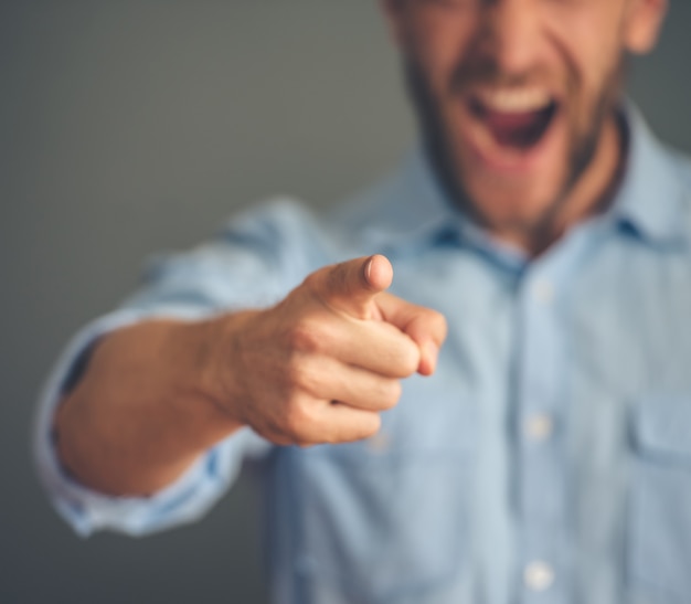 Angry businessman pointing and screaming at camera