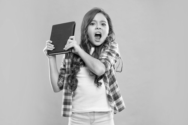 Angry child hold book on blue background school