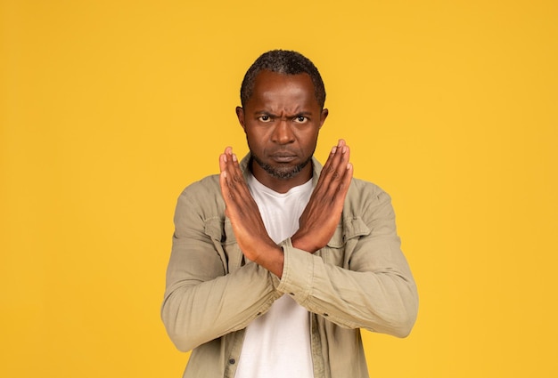 Angry confident sad middle aged african american man in casual crossed arms doing stop sign