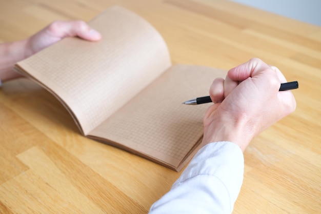 Angry person clenched his fist with a pen next to an open notebook