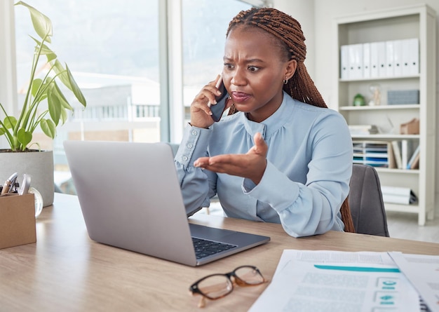 Angry phone and stressed black woman on a business call about tax audit and compliance email on laptop at office desk Employee working mad internet and tech glitch on the website of the company