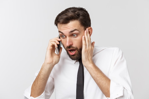 Angry and serious businessman talking on the phone over gray