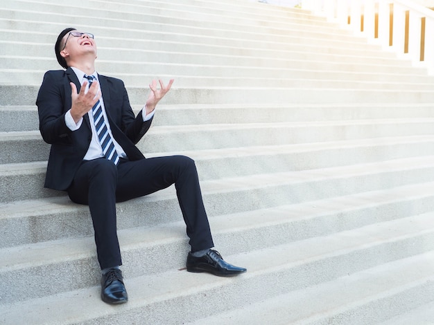 Angry strain happy businessman is sitting on the stairs 