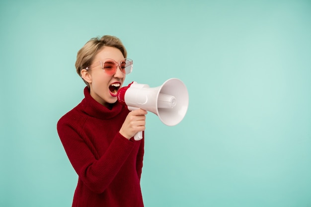 Angry woman in pink sunglasses candidate with a megaphone on blue background - Image