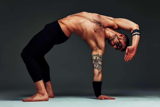 Animal instinct fitness instructor sportsman showing his incredible flexibility with an animal flow move in studio against a gray background