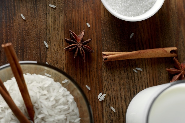 Anise cinnamon stick and rice grains on a wooden board Rice milk and sugar on the board