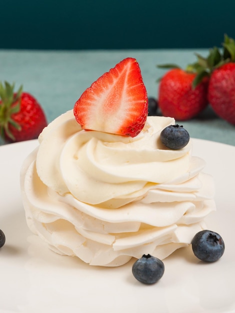 Anna Pavlova dessert decorated with strawberries and blueberries closeup