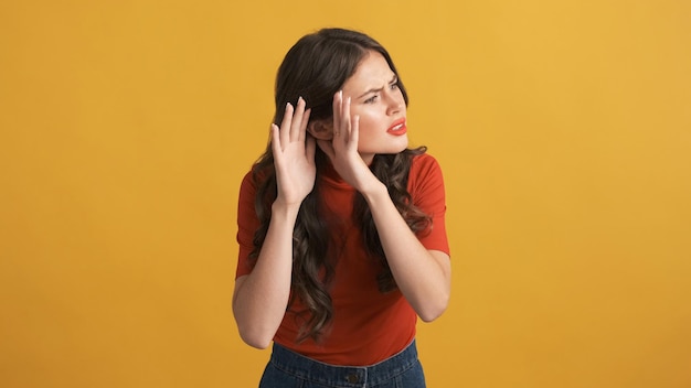 Annoyed brunette girl in red top trying to hear what saying over colorful background Not hearing expression