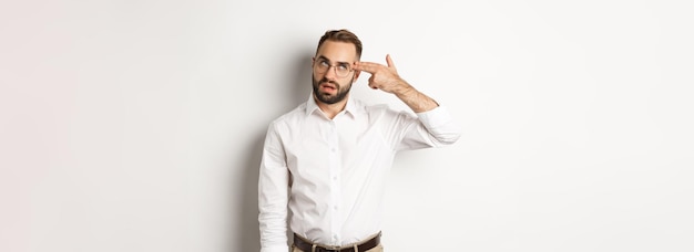 Annoyed man making shooting in head and roll eyes standing distressed over white background