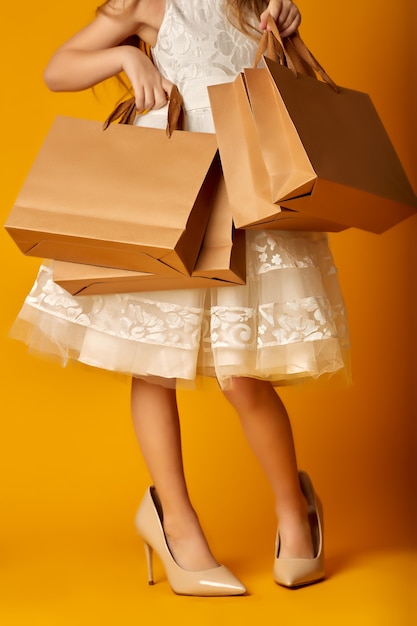 Anonymous girl in stylish clothes and oversized high heeled shoes taking paper bag