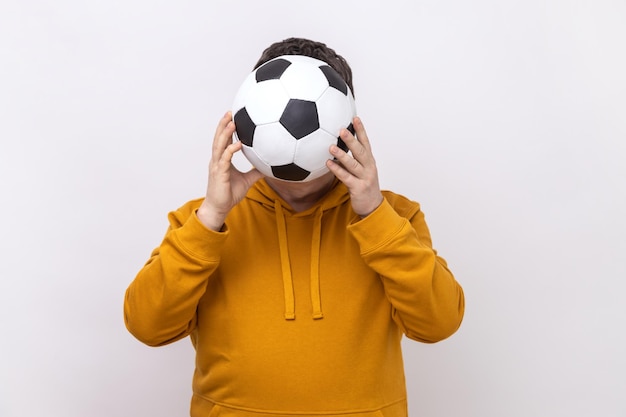 Anonymous unknown man hiding behind soccer ball football fan covering his face during match