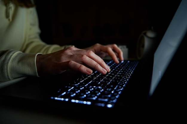 Anonymous woman working on laptop at night